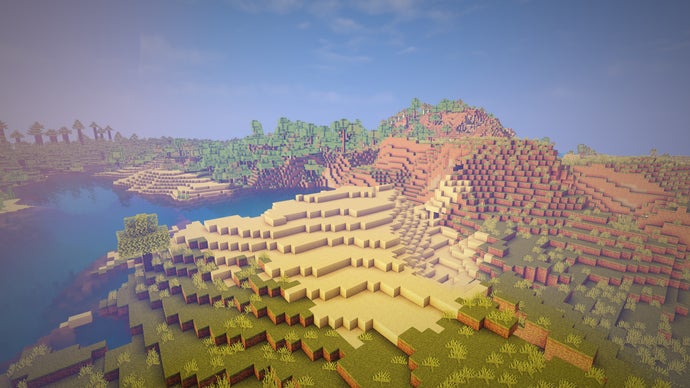 Vista aérea de uma paisagem no servidor Minecraft, com areia em primeiro plano, floresta ao fundo e um lago à esquerda.